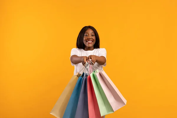 Feliz dama negra extendiendo bolsas de compras en amarillo —  Fotos de Stock