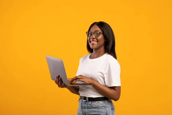 Happy african american woman with glasses holding laptop and smiling — Stock Photo, Image