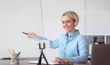 Online okul. Kadın öğretmen boş tahtaya işaret ediyor, web 'de ders veriyor, öğrencilere yeni materyalleri anlatıyor.