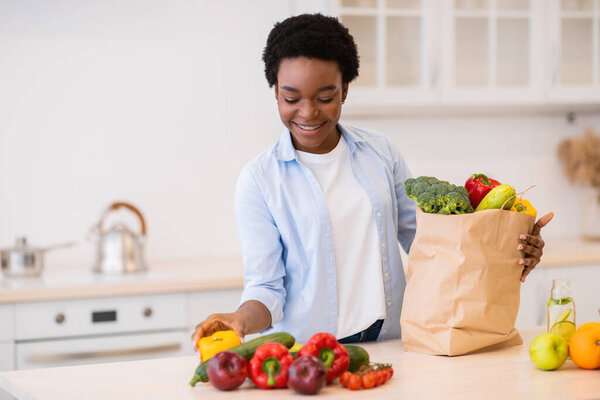 Happy Black Lady Unpacking After Grocery Shopping In Kitchen Indoors