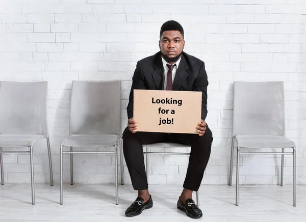 공식 양복을 입은 아프리카계 미국인이 JOB 표지판을 노려보며 사무실 로비에서 일자리 인터뷰를 기다리고 있습니다. — 스톡 사진