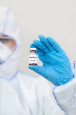 Tehlikeli madde giysisi, eldiven, maske ve gözlüklü doktor Covid-19 aşısı tutuyor.