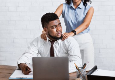 Bayan patron, çekici erkek astına cinsel tacizde bulunuyor. Şirket ofisinde ellerini omzuna koyuyor.