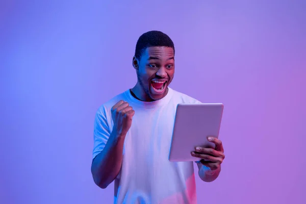 Online Win ( 영어 ). 디지털 태블릿으로 성공을 축하하는 즐거움을 누리는 아프리카계 미국인 남자, — 스톡 사진