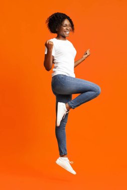 Kazanan siyah kadın ayağa fırlıyor ve komik figürler gösteriyor.