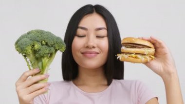 Hamburger ve Brokoli Yiyecekleri Seçen Asyalı Kadın, Beyaz Arkaplan