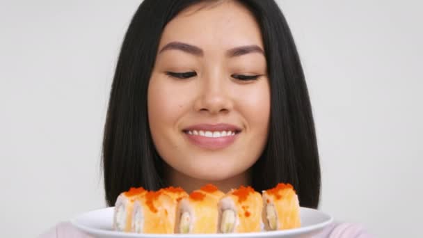 Woman Smelling Sushi Rolls And Winking At Camera, White Background — Stock Video