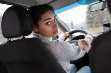Zarif kadın sürücü arka koltuğa bakar ve yolculara emniyet kemerini takmalarını söyler.