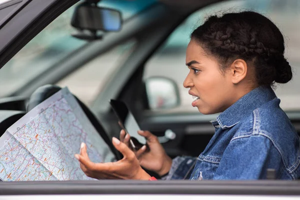 Angry saddened millennial african american female driver spreads arms to sides and not understanding how to find the way