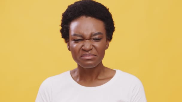 Közelkép portré fiatal elégedetlen afro-amerikai nő szaga büdös szag, becsukja az orrát, narancs háttér — Stock videók