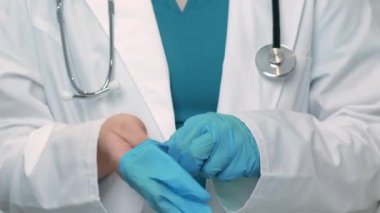 Doktorun randevudan önce tek kullanımlık koruyucu eldivenleri giymesine yakın çekim, yavaş çekim.