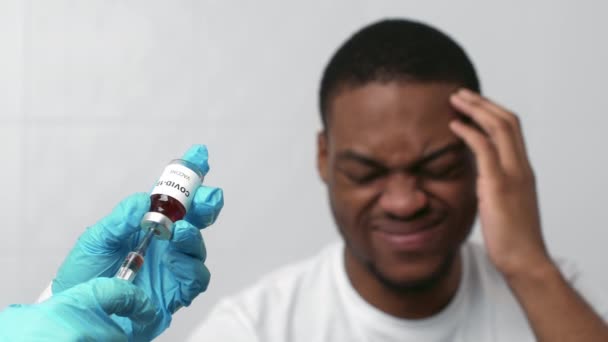 Angst voor injecties. Dokter handen nemen vaccin naar de spuit, Afrikaans-Amerikaanse man voelt zich in paniek op de achtergrond — Stockvideo