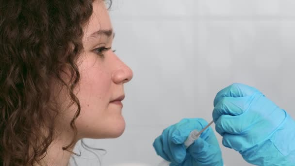 Trabajadora de laboratorio que toma muestra de la garganta PCR para la prueba de Covid-19 de una paciente joven — Vídeos de Stock