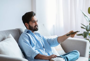 Arap adam evde televizyon izliyor. Doğulu Adam Oturma Odasında Dinleniyor