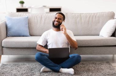 Kapalı alanda dizüstü bilgisayarla konuşan Afro-Amerikalı adam.