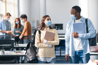 Uluslararası öğrenciler tıbbi maske takıp konuşuyorlar.