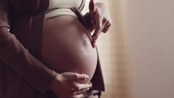 Крупный план беременной женщины, играющей животом, наступающей на него пальцами, замедленной съемки, пустого пространства — стоковое видео