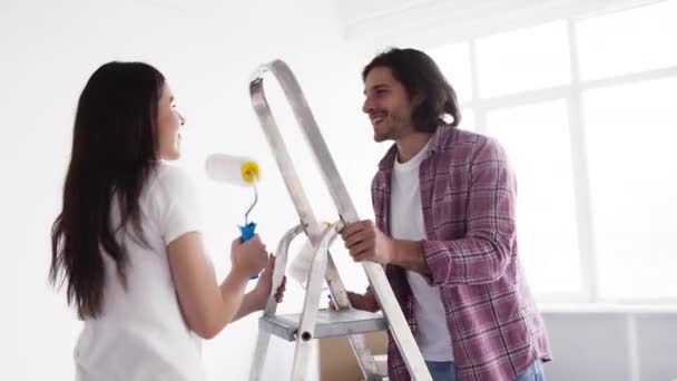 Junges glückliches Ehepaar tanzt und albert mit Arbeitsgeräten herum und repariert in ihrer Wohnung — Stockvideo