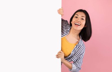 Asyalı kadın beyaz reklam panosunun arkasına saklanıyor.