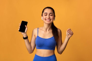 Spor Giyim 'de Gülümseyen Kadın Müzik Dinleyen Cep Telefonu