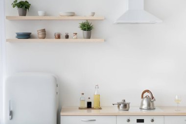 Beyaz ve ahşap malzeme, küçük buzdolabı, ısıtıcılı soba, bir şişe sos.