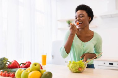 Neşeli Afrikalı kadın Sebze salatasını seviyor Mutfakta yemek yiyor