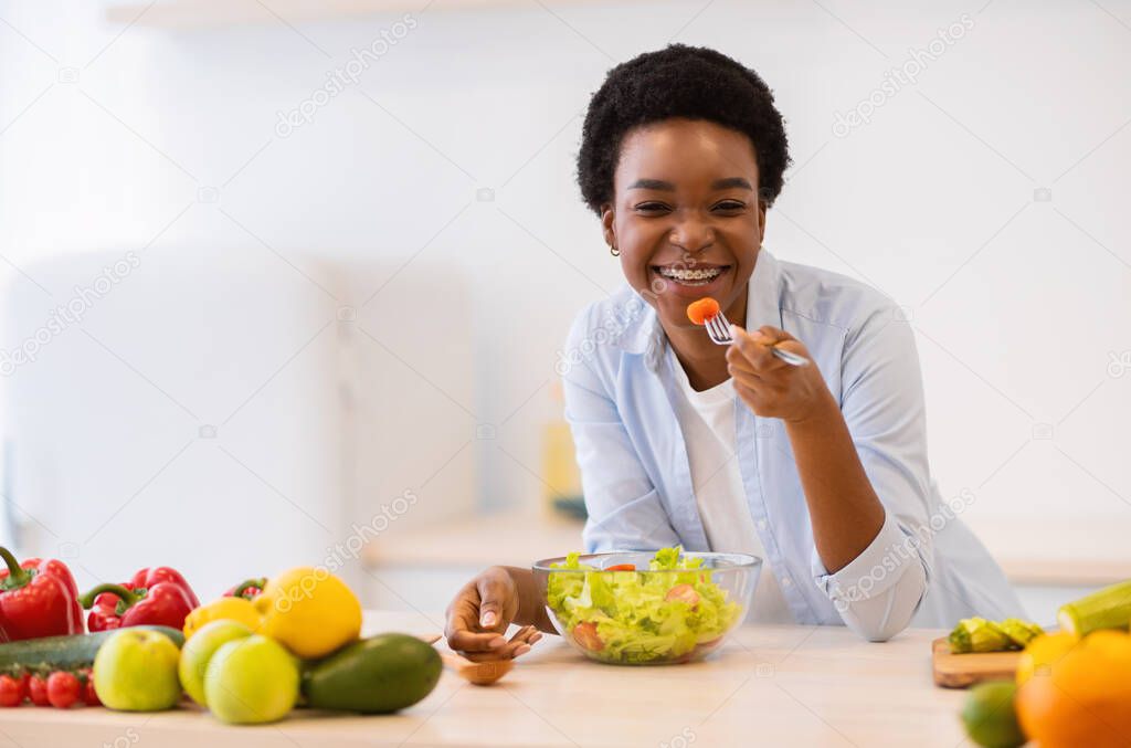 Happy Black Woman Eating Fresh Vegetable Salad In Kitchen Indoor