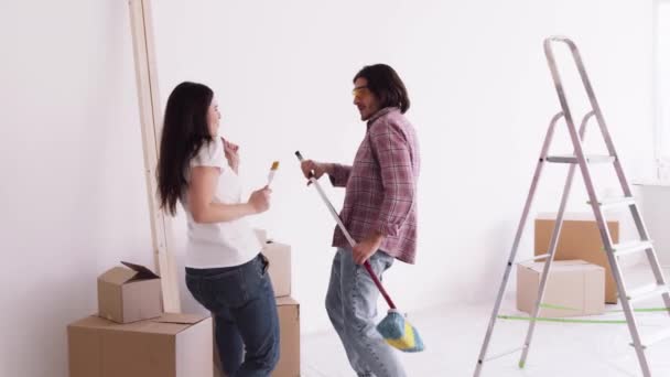 Feliz joven familia cantando bailando junto con herramientas de trabajo durante la redecoración del apartamento y la construcción de viviendas — Vídeos de Stock