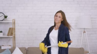 Duygusal genç kadın paspasa şarkı söylüyor, ev temizliği sırasında eğleniyor, gitarlı popüler bir rock yıldızı gibi hissediyor.