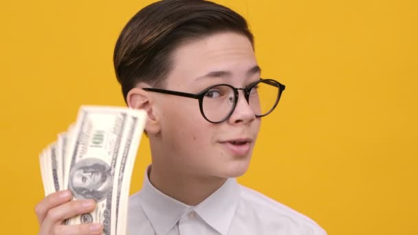 Rico adolescente chico celebración dinero sacudiendo dólar notas, fondo amarillo — Vídeos de Stock