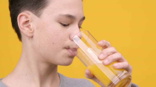 黄色の背景にオレンジジュースの十代の男の子の飲料ガラス — ストック動画