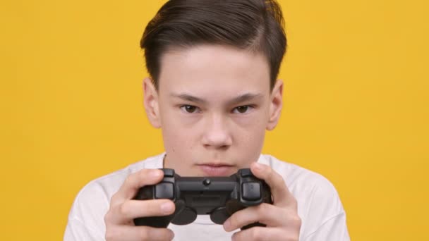 Gericht tiener jongen spelen video game over gele studio achtergrond — Stockvideo