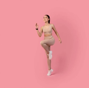 Pembe Arkaplanda Koşan ve Egzersiz Yapan Kadın