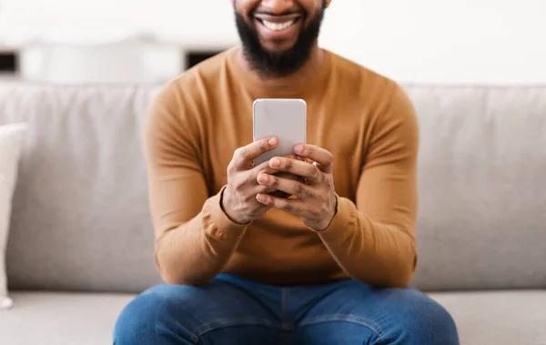 Unrecognizable African Man Using Smartphone At Home, Focus On Phone
