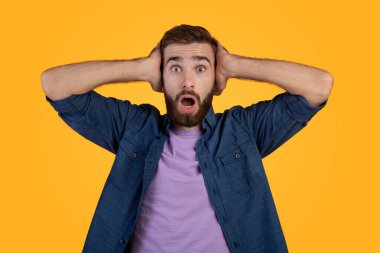 Şaşırmış Kafkasyalı adam şaşkınlık içinde ağzını açıyor, turuncu stüdyo arka planında şaşkın ve şaşkın bakıyor