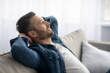 Yakışıklı orta yaşlı adam evdeki kanepede dinleniyor.
