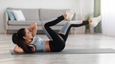 Aktif genç kadın evde egzersiz yapıyor, mekik çekiyor.