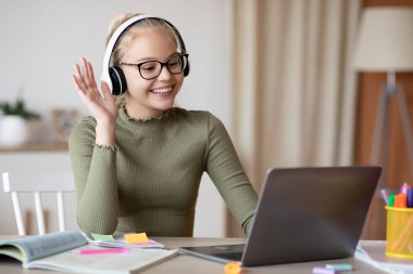 Pozitif sarışın kız öğretmeniyle video konferansı yapıyor.