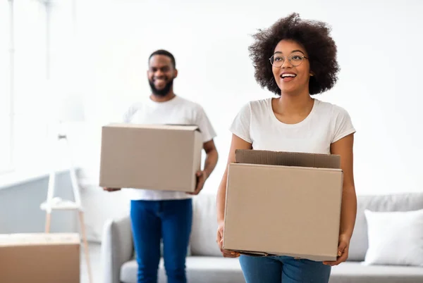 Cônjuges negros alegres transportando caixas móveis entrando em nova casa juntos — Fotografia de Stock