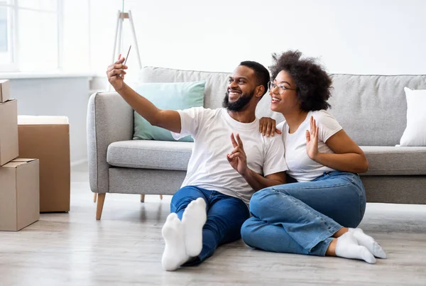 Afrikanische Ehepartner machen Selfie-Posen zwischen Umzugskartons, die drinnen sitzen — Stockfoto