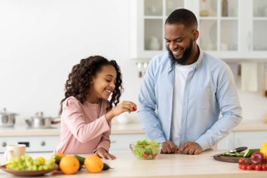 Neşeli Afrikalı baba kızına salata yapmayı öğretiyor.