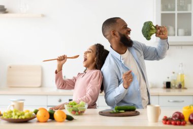 Siyah baba ve kızı mutfakta birlikte şarkı söylüyorlar.