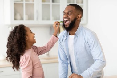 Neşeli Afrikalı kız taze salata pişiriyor.