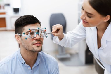 Optometrist erkek hastaların görüşlerini deneme çerçevesi ile kontrol ediyor