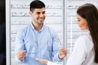 Kadın optometrist adamın yeni gözlük seçmesine yardım ediyor.