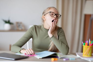 Evde ödev yaparken yorgun hisseden uykulu genç kız.