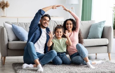 Arabic parents making symbolic roof of hands above their cute little daughter clipart