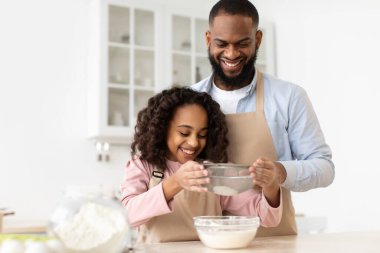 Neşeli siyah adam ve kızı hamur hazırlıyor.