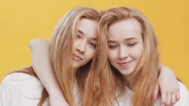 Tutup potret dua muda berambut merah kembar memeluk dan menunjukkan sikap damai ke kamera, latar belakang studio oranye — Stok Video