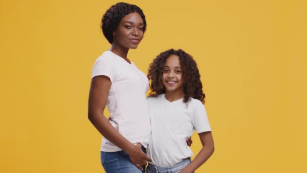 Mutlu siyah anne ve kız birbirlerine bakıyorlar ve kameraya gülümsüyorlar, turuncu arka planda sarılıyorlar. — Stok video